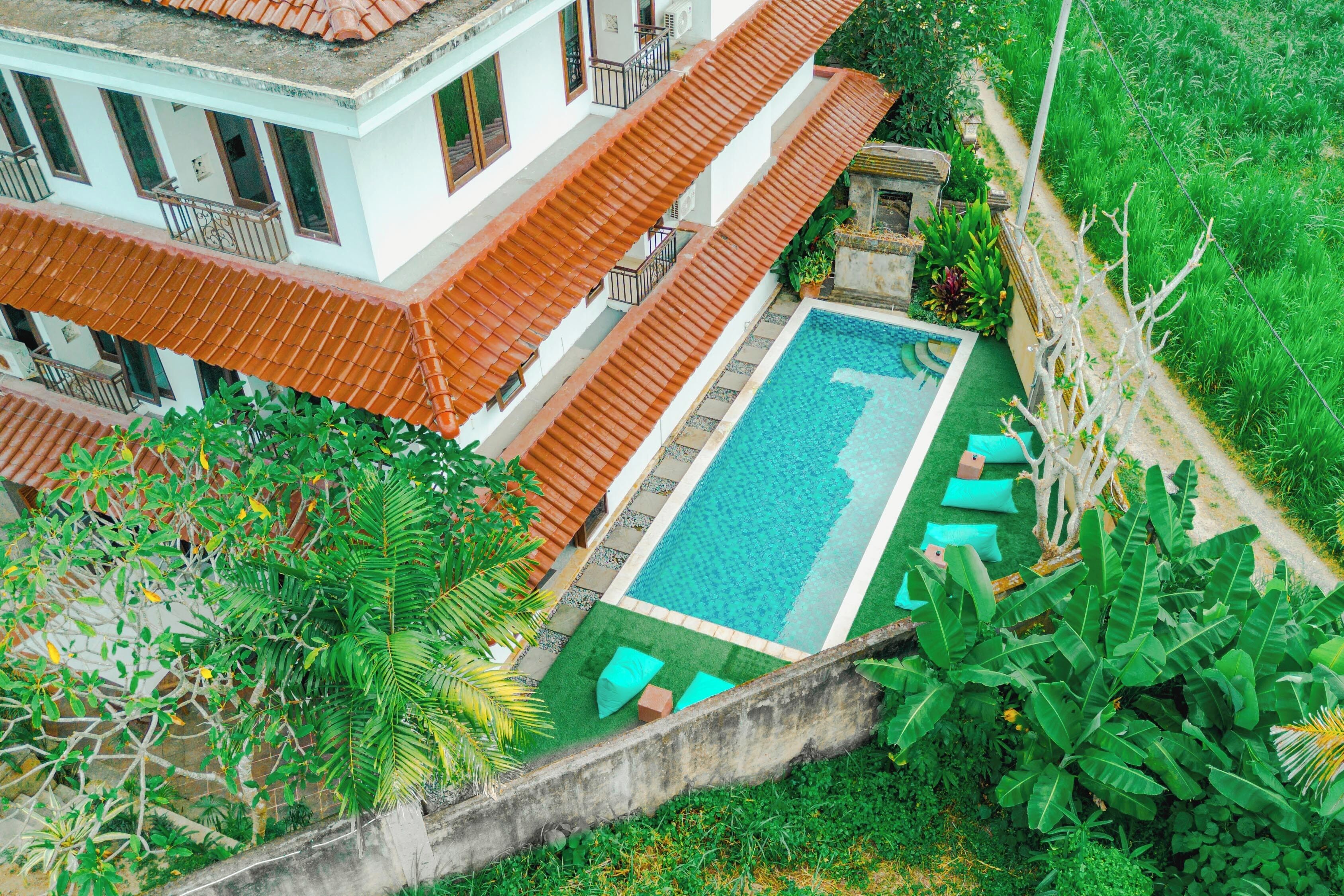 A multi-story building with a swimming pool, surrounded by lush greenery and a well-maintained garden.