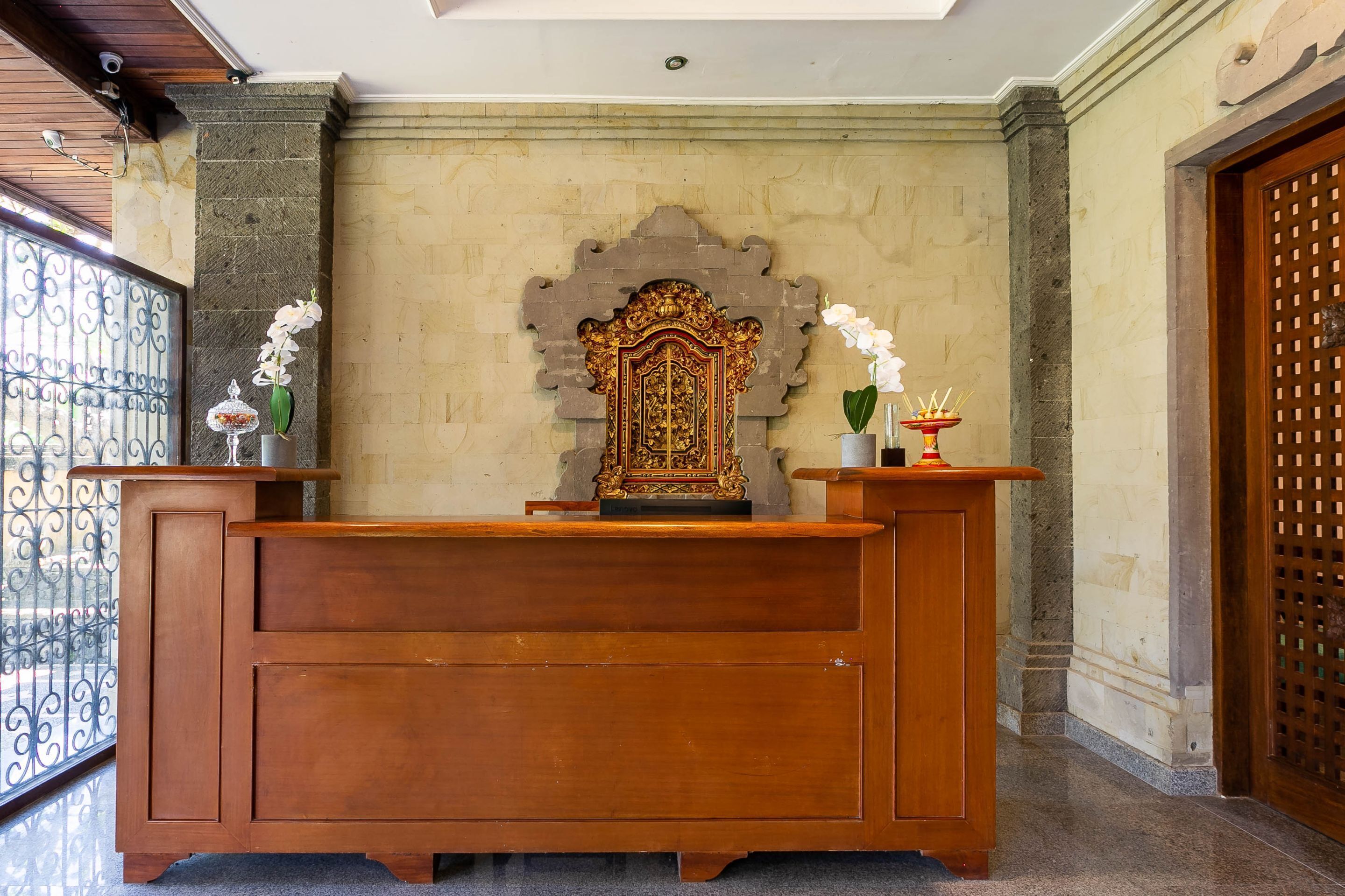 A reception desk with a decorative screen, a vase with white flowers, and a small incense burner.