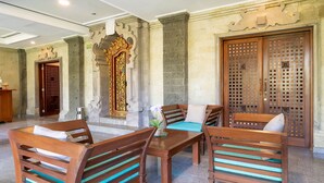 A lobby with wooden furniture, stone columns, and a decorative door.