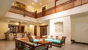 A spacious, multi-level hotel lobby with wooden furniture, a reception desk, and a staircase.