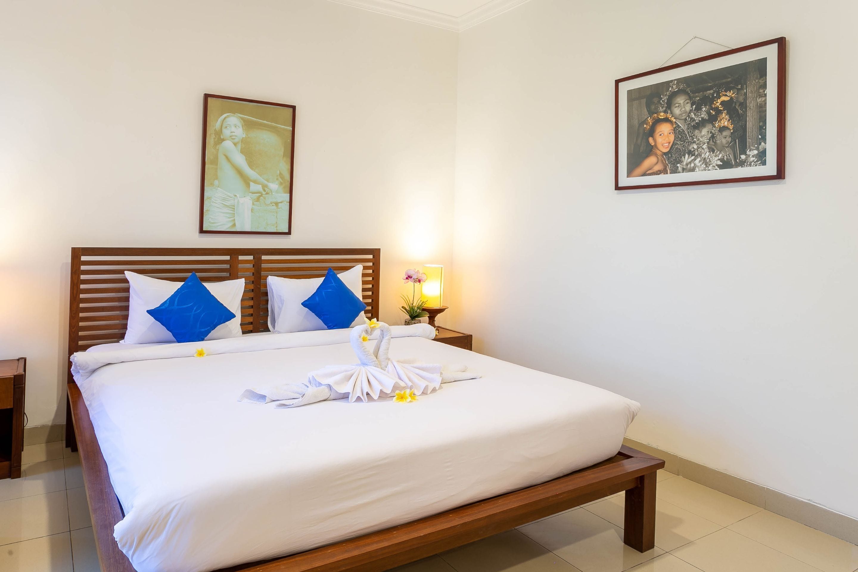 A neatly made bed with a wooden headboard, white bedding, and decorative towels.