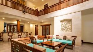 A spacious lobby with wooden furniture, a high ceiling, and a decorative wall carving.