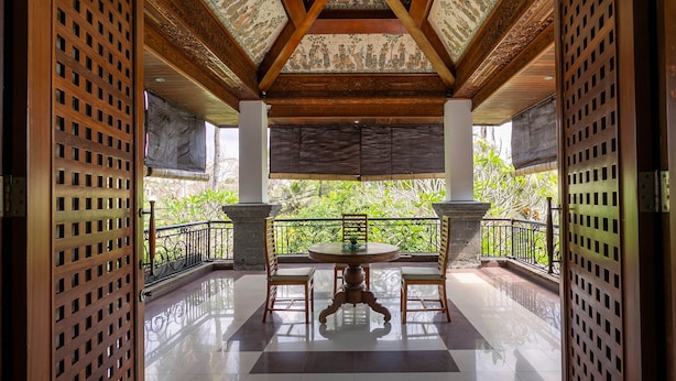 A covered outdoor area with a round table and chairs, surrounded by a wooden lattice fence.