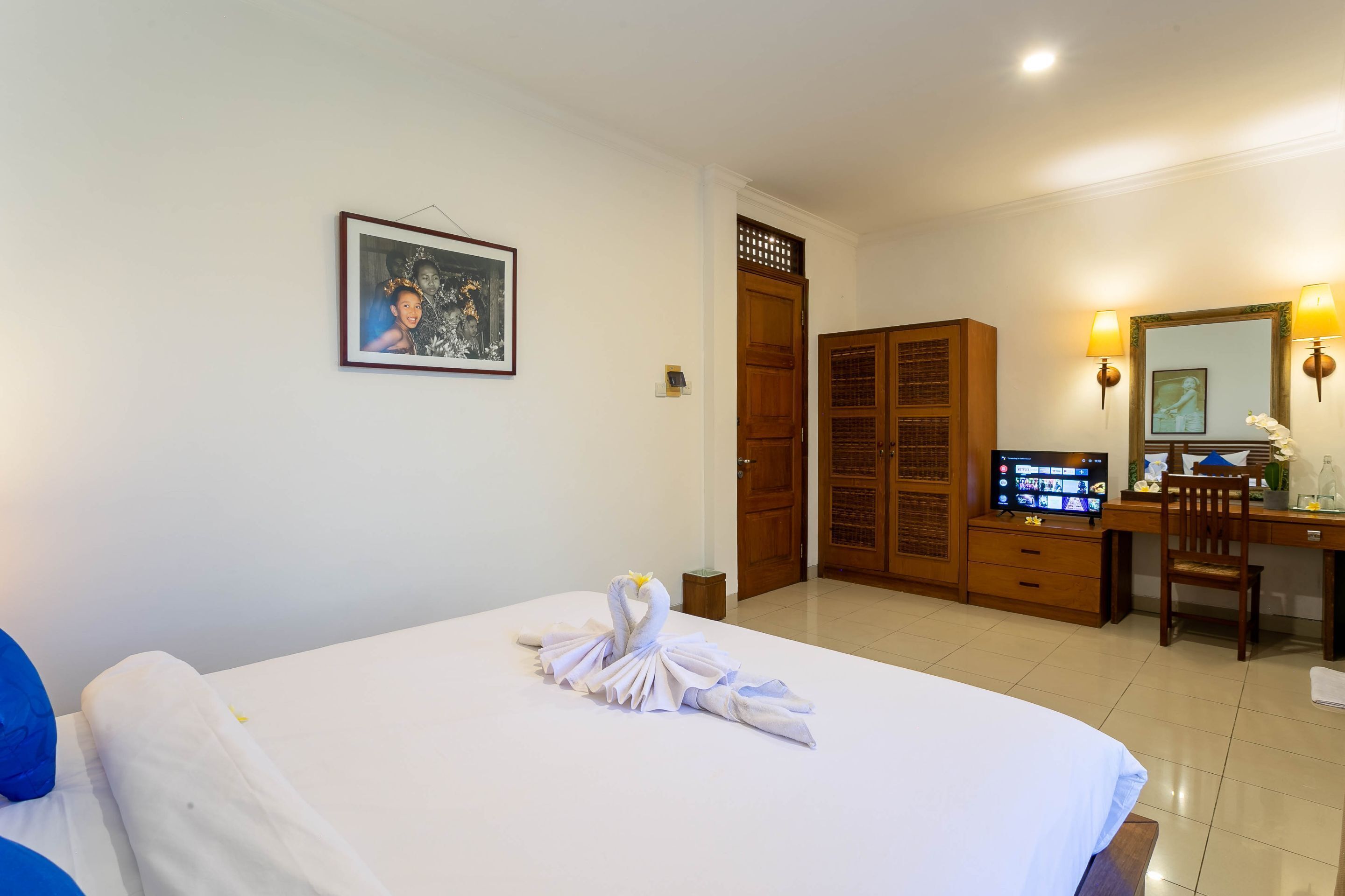 A hotel room with a bed, a desk, a television, and a wardrobe.