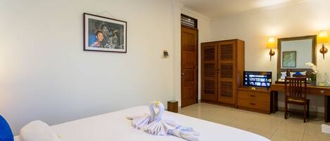 A hotel room with a bed, a desk, a television, and a wardrobe.