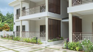 A multi-story residential building with balconies, a garden area, and a paved walkway. - Sahaj Holiday Apartments (Praslin Island)