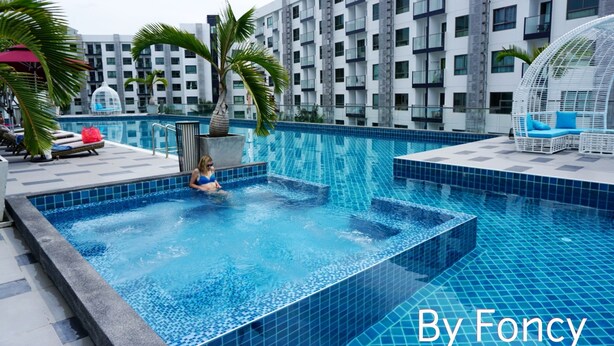 Ein Pool auf dem Dach mit klarem, blauem Wasser, umgeben von modernen Gebäuden und Palmen.