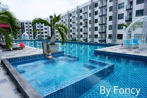 A rooftop pool with a clear blue water feature, surrounded by modern buildings and palm trees.