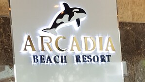 Schild für das Arcadia Beach Resort mit einem Delphin-Logo.