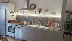 Una cocina moderna con electrodomésticos de acero inoxidable, horno empotrado y un lavamanos grande.