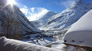Un village de montagne enneigé, avec des bâtiments traditionnels, un ciel dégagé et un soleil éclatant.