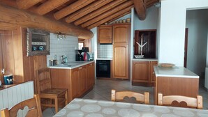 Une cuisine de taille réduite, dotée de meubles en bois, d’un évier et d’un coin repas avec une table et des chaises.