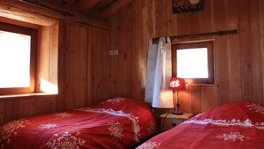 Une chambre en bois avec deux lits, une fenêtre et une lampe.
