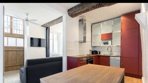 A modern kitchen with a wooden table, red cabinets, and a built-in microwave. - Suit Du Lion/AC Historic Flat, Marais, 4-5 Guests (Paris)