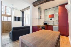 Une cuisine moderne avec une table en bois, des placards rouges et un four à micro-ondes encastré.