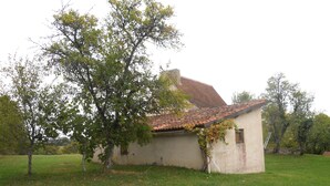 A small, single-story building with a tiled roof and a tree in front. - Former sheepfold in the middle of an orchard and a 2 ha meadow (Ussel)
