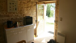 A kitchen with a stone wall, a framed menu, a coffee maker, a toaster, and a television. - Former sheepfold in the middle of an orchard and a 2 ha meadow (Ussel)