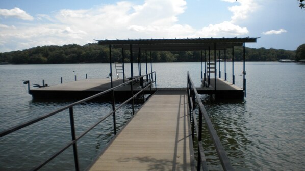 Un muelle de madera que se adentra en aguas tranquilas, con un área de descanso cubierta al final.