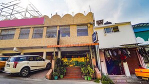 A building with a storefront, steps leading up to the entrance, and a parked car in front. - FabHotel Roshan Residency (Kodaikanal)