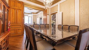 Ein formeller Speisesaal mit langem Tisch, mehreren Stühlen und einer Chandelier.