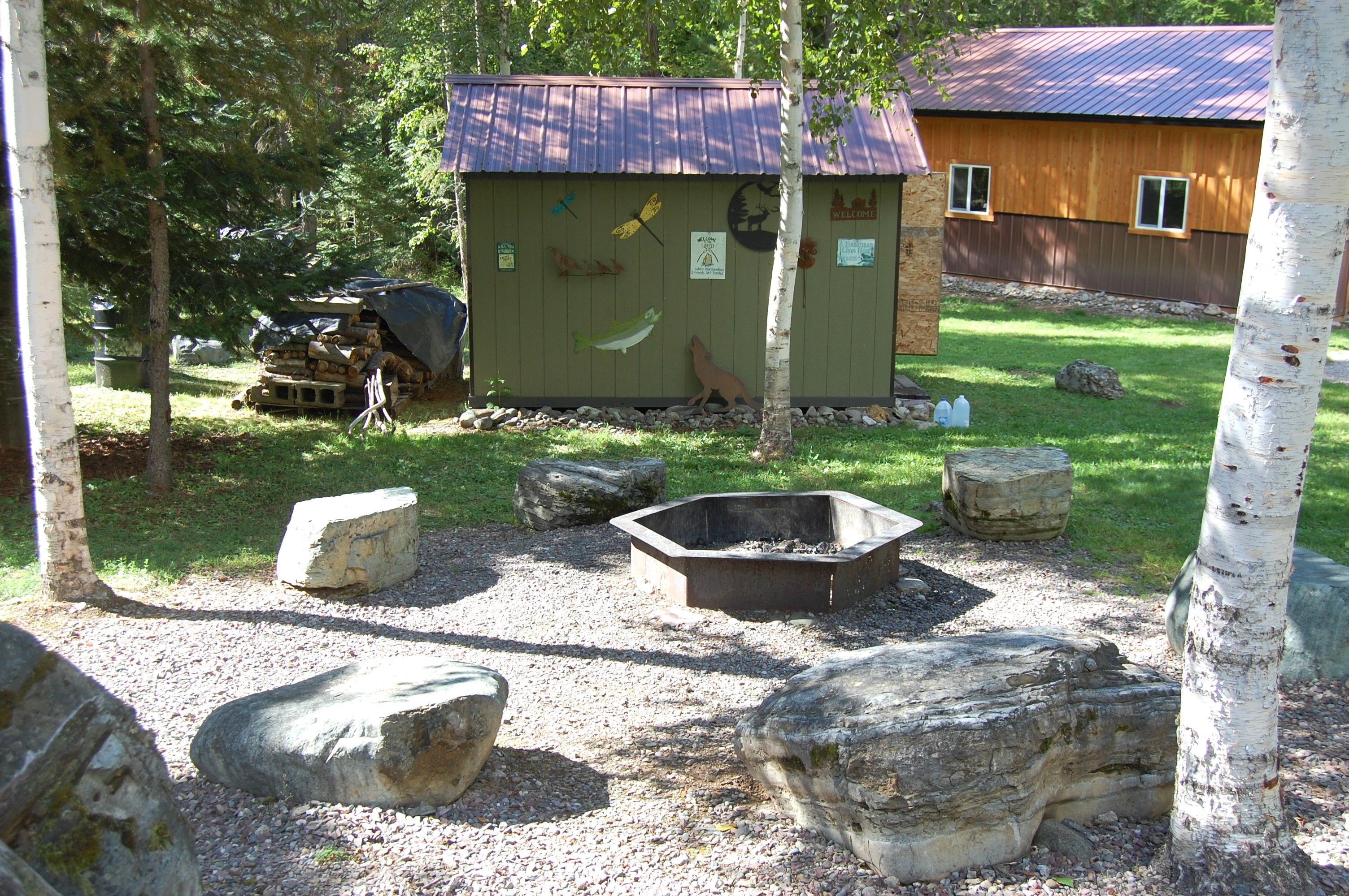 Ein rustikales Holzhaus mit Metalldach, umgeben von Steinen und Bäumen.