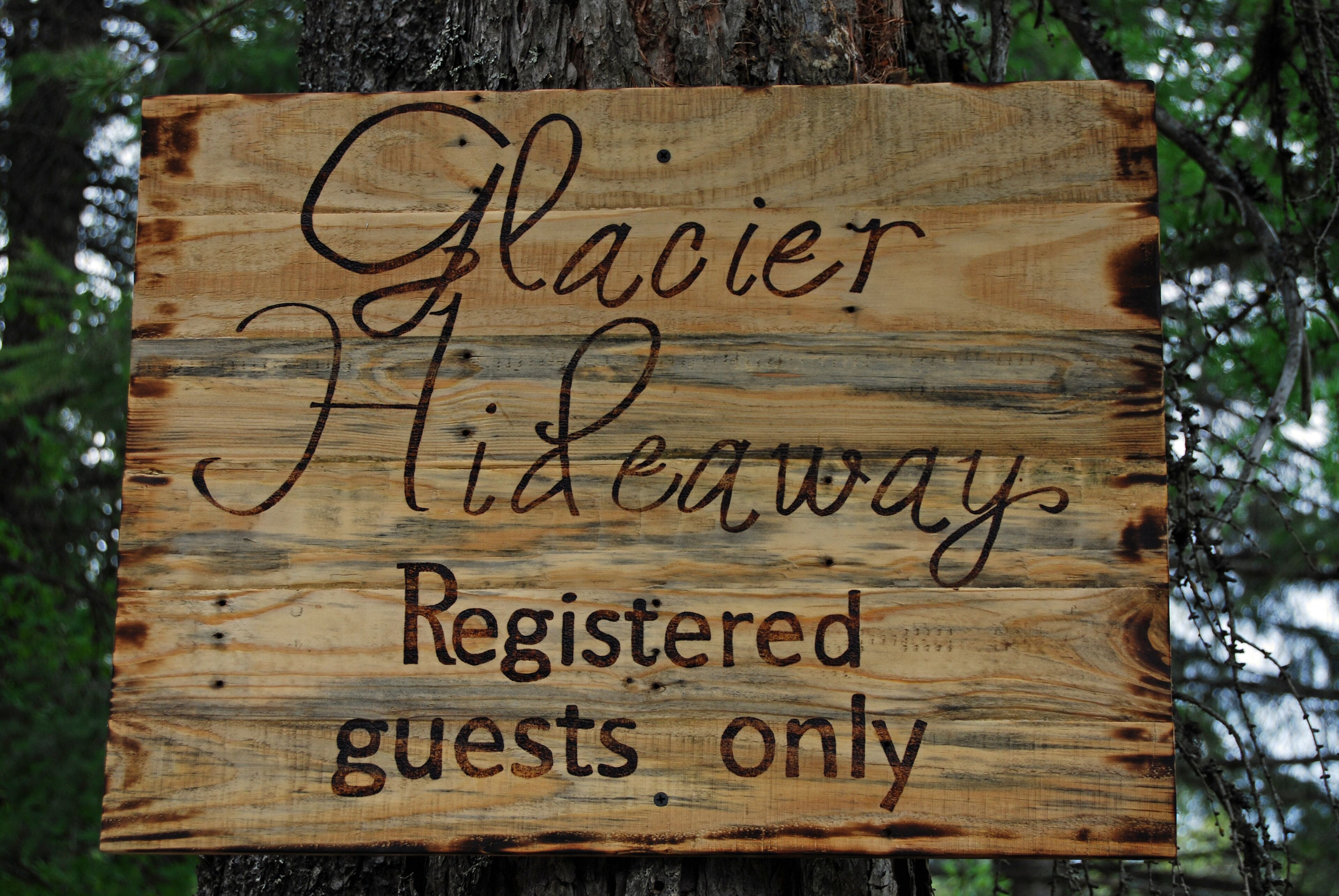 Un letrero de madera con el texto 'Solo huéspedes registrados en Glacier Hideaway'.