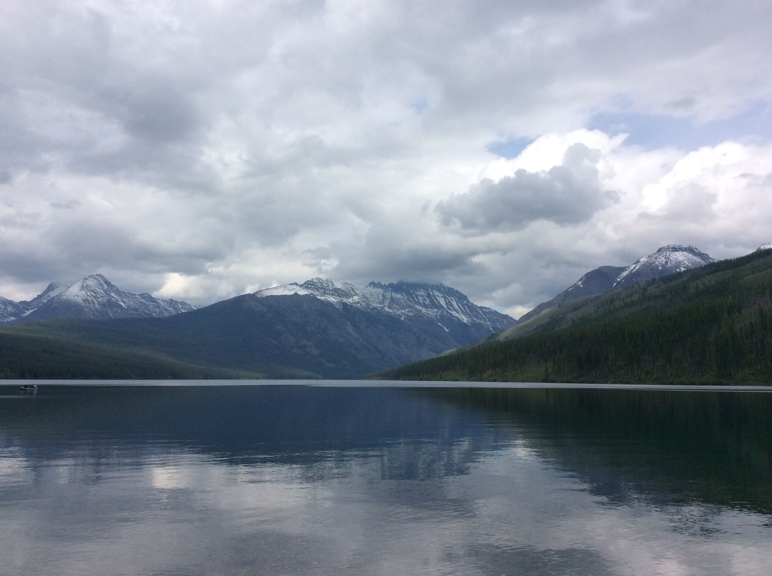 Un lac paisible, avec des montagnes en arrière-plan.