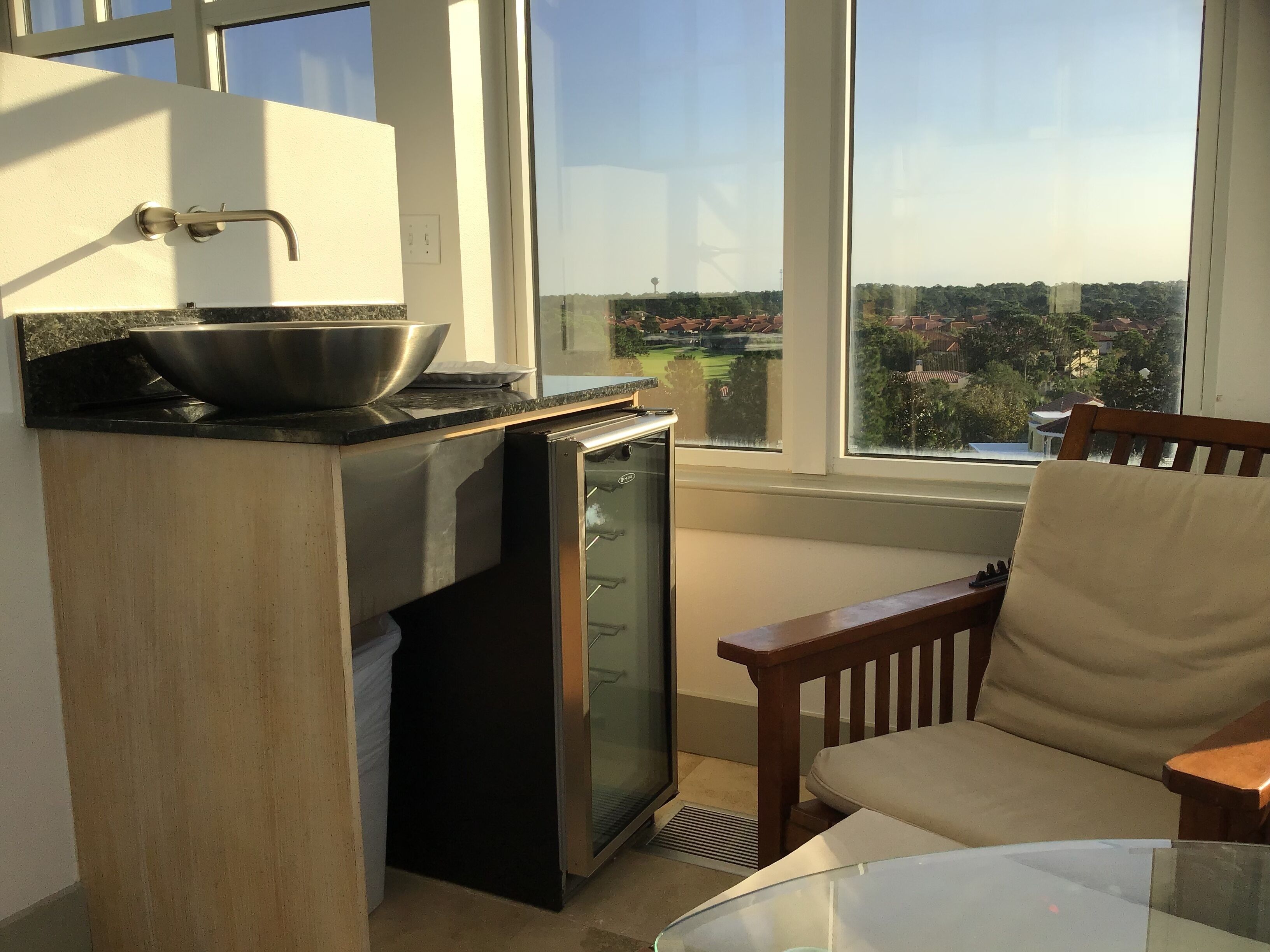 Uma cozinha compacta com fogão embutido, um refrigerador pequeno e uma janela com vista para a cidade.
