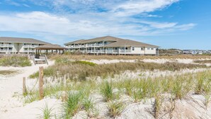 A beachfront hotel with multiple floors, a covered walkway, and a sandy beach area. - SSV 207: Oceanfront Condo with Pool and Views! (Oak Island)