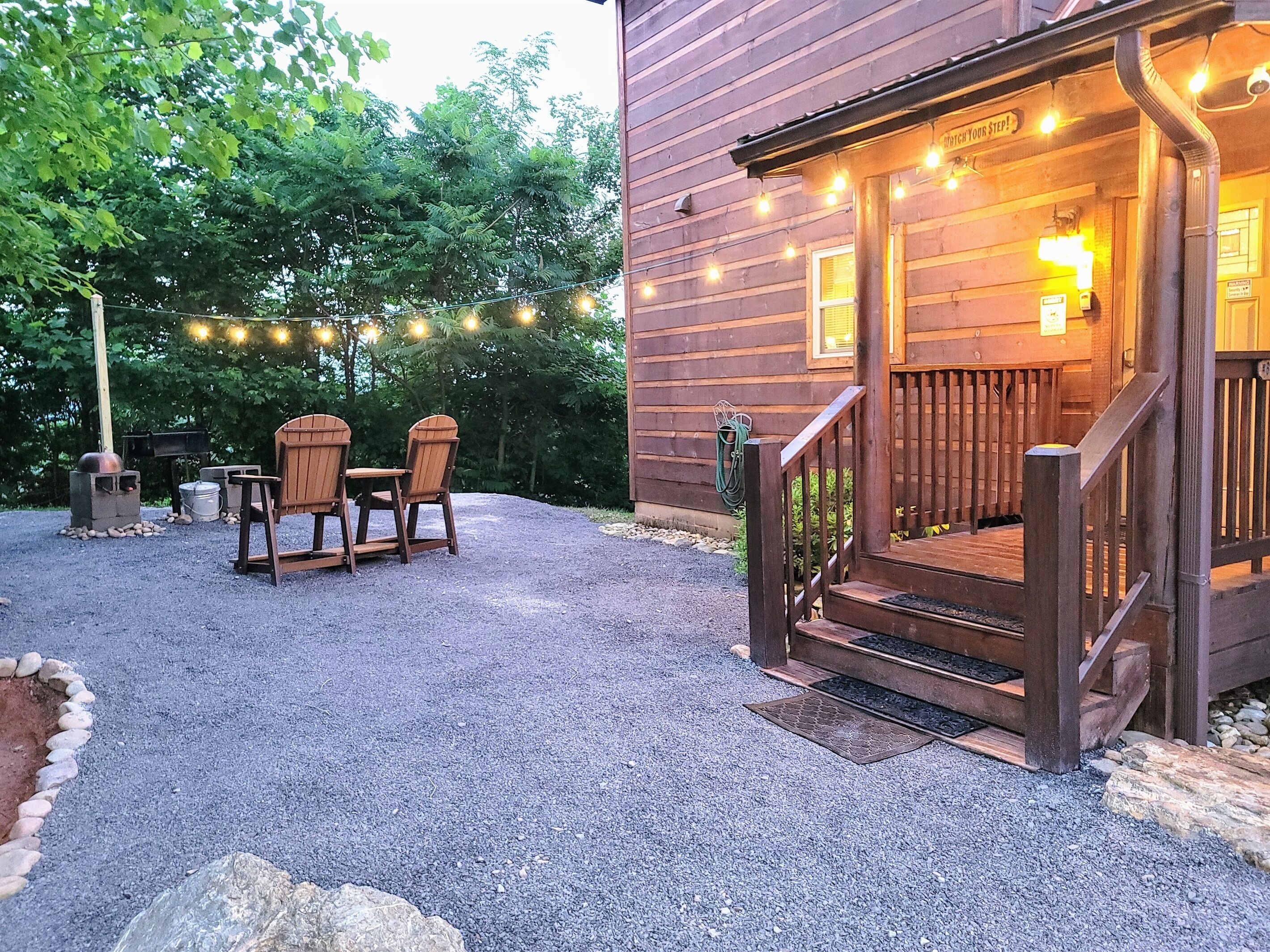 Una cabaña de madera con un porche, mobiliario exterior e iluminación con guirnaldas.