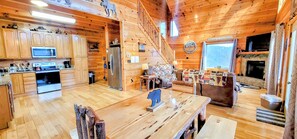 L’intérieur de la cabane est doté de planchers en bois, d’une cuisine équipée d’appareils modernes, d’un coin repas avec une table et des chaises, d’un canapé et d’une cheminée.