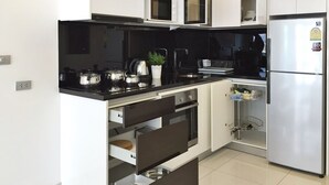 A modern kitchen with white cabinets, a black countertop, stainless steel appliances, and a built-in oven.