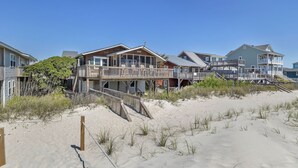 Ein strandnahes Anwesen mit mehreren Häusern, darunter ein großes Haus mit einer Holzterrasse und ein kleineres Haus mit einem Balkon.