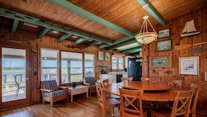 L’intérieur d’un chalet en bois comprend un coin repas, une cuisine et de grandes fenêtres donnant sur un paysage magnifique.