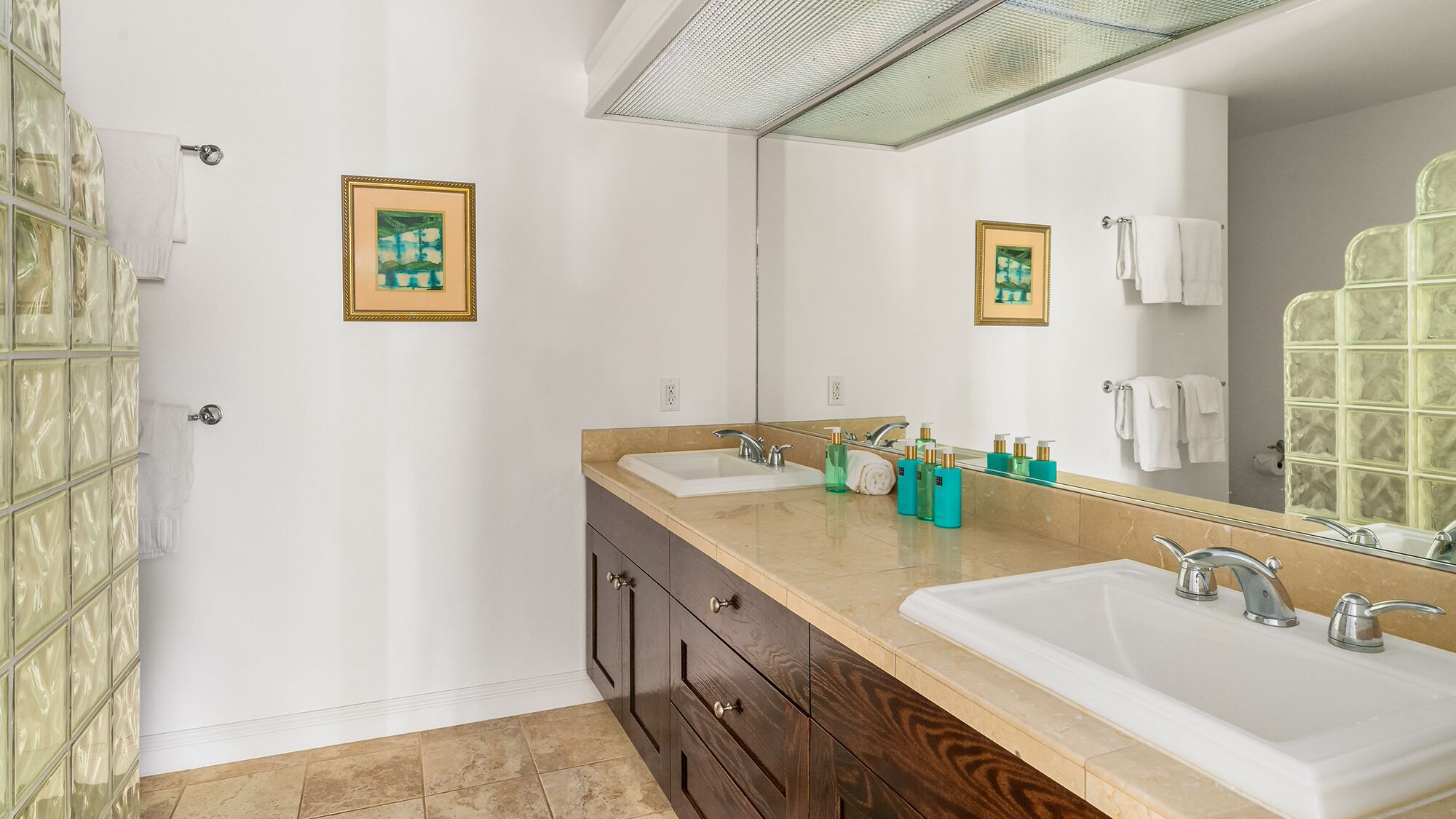 Une salle de bain avec deux lavabos, un grand miroir et une douche à l’italienne.