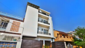 A multi-story residential building with balconies, a gated entrance, and a clear blue sky. - Hotel Aarya (Lucknow)