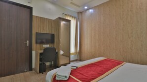 A hotel room with a bed, a desk, a chair, a television, and a wardrobe. - Hotel Aarya (Lucknow)