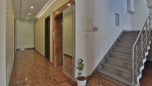A modern interior with a marble floor, a staircase, and a potted plant. - Hotel Aarya (Lucknow)