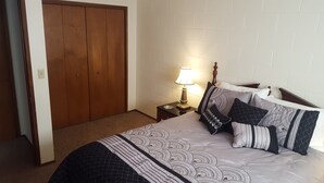 A bedroom with a bed, pillows, a nightstand, a lamp, and a wooden wardrobe. - West Yakima - Clean - Safe - Netflix - 810 - ONWU-LLC (Yakima)