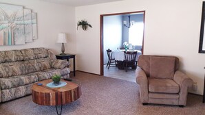 A living room with a sofa, armchair, coffee table, and a dining area in the background. - West Yakima - Clean - Safe - Netflix - 810 - ONWU-LLC (Yakima)