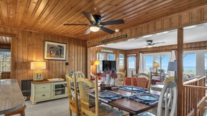 Un interno in legno con zona pranzo, ventilatori a soffitto e ampie finestre.