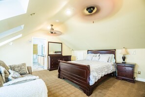 Une chambre à coucher avec un grand lit, une commode, une table de chevet et un ventilateur de plafond.