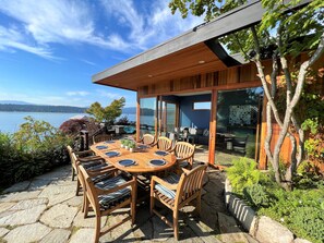 Terraza de madera con mesa y sillas con vista a un lago.