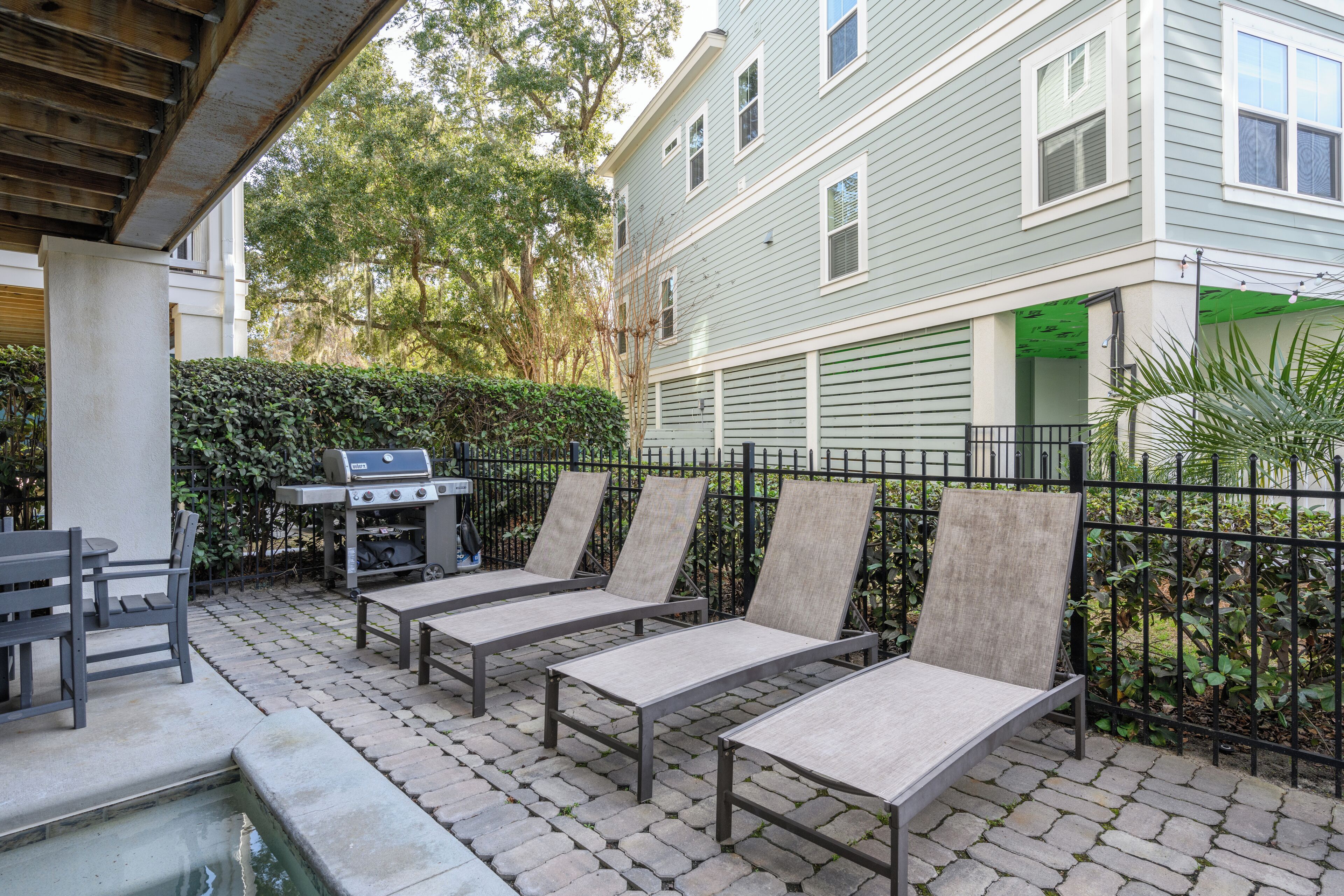 An outdoor patio with lounge chairs, a grill, and a swimming pool.
