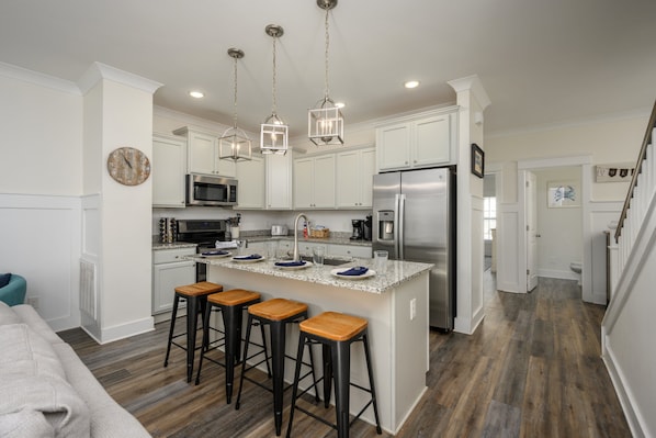 A modern kitchen with white cabinets, stainless steel appliances, and a central island with bar stools.