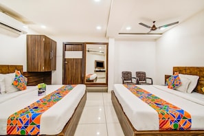 A hotel room with two beds, a wardrobe, a mirror, a ceiling fan, and a bathroom visible through an open door. - FabHotel Rajnandani Residency (Indore)