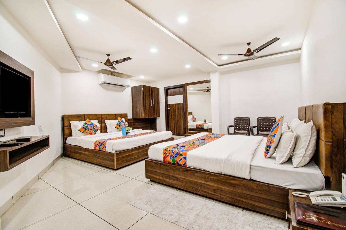 A hotel room with two wooden beds, a TV, a desk, and a phone.
