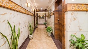 A hallway with marble walls, wooden accents, and potted plants. - FabHotel Rajnandani Residency - Bhanwarkuan (Indore)