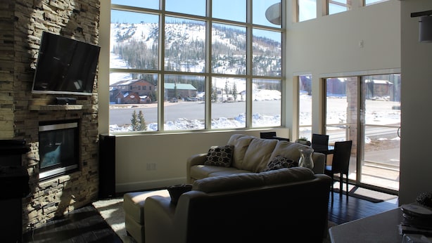 A living room with a stone fireplace, a large window with a view of a snowy mountain, and a modern sofa.