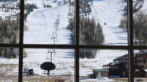 A view through a window of a snowy mountain landscape with a ski lift, buildings, and a road.